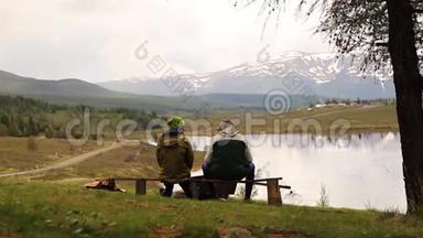 两个成年人的后景，坐在长凳上，花时间环顾<strong>山湖美景</strong>